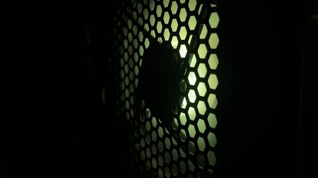 dark shot of spinning fan behind honeycomb mesh pattern