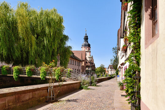 Ettlingen, Germany - August 13th 2025: Street in old historic city center with flower-covered bridge over Alb creek in Ettlingen