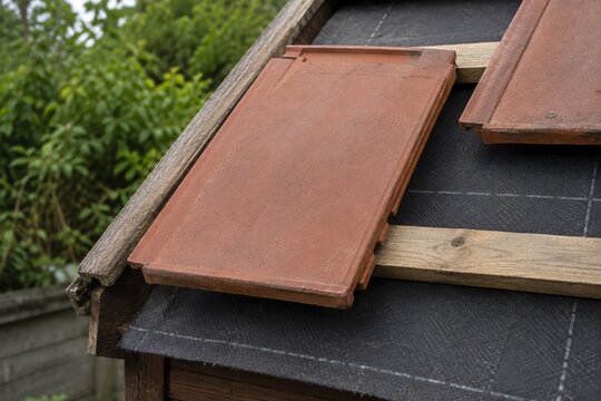 Terracotta roof tiles resting on wooden battens above exposed underlay