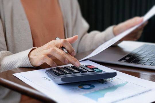 Woman hand using calculator holding financial report paper. Representing concepts of accounting, tax budget calculation and business finance.