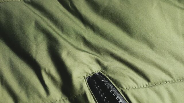 Close up shot of olive green jacket pocket zipper. Detail of textile windproof casual apparel. Outerwear element texture on fabric banner.