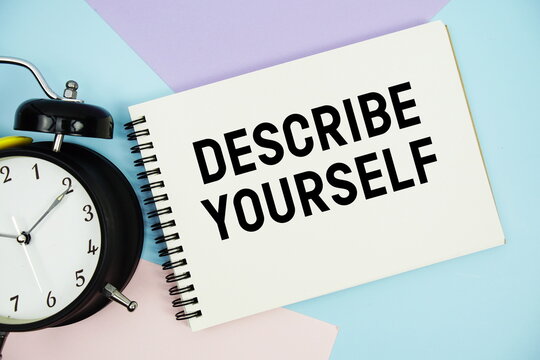 Describe Yourself text written on notepad with alarm clock flat lay on multicolor pastel background