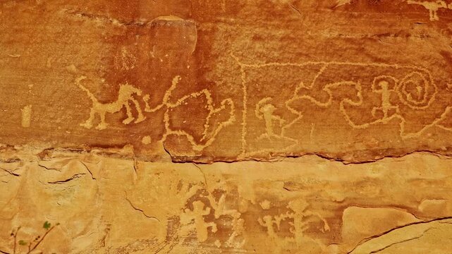 Intricate ancestral Native American rock carvings etched into sheer canyon sandstone walls flank Petroglyph Point Trail in Mesa Verde