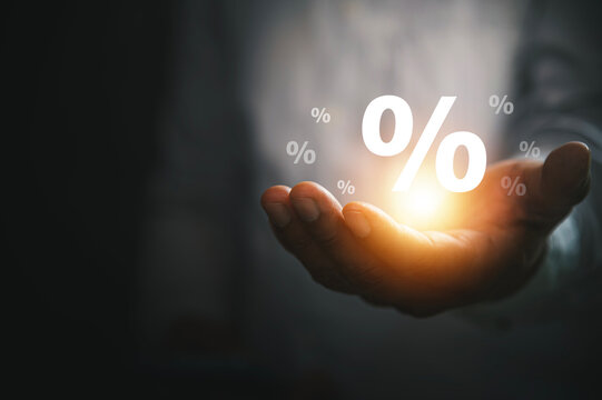 Interest Rate and Financial Growth Concept with Businessman Hand Holding Glowing Percentage Symbols.