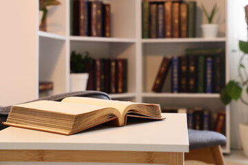 Education and lifelong learning, open book on a desk in a library or home study with blurred bookshelves in the background for academic research © Pixel-Shot