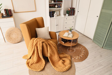 Cozy home interior hygge lifestyle and relaxation with mustard armchair chunky knit blanket open book and wooden furniture in bright room © Pixel-Shot