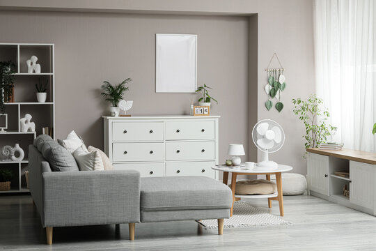 Interior design and home comfort, modern living room with grey sofa and white dresser empty picture frame for mockup and summer cooling fan