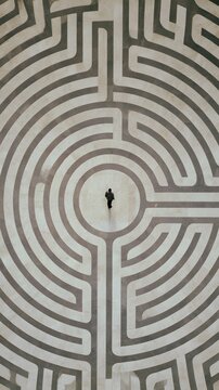 Top down view of a person standing in the center of a stone maze