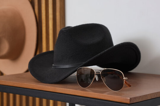 Western fashion and travel style, black felt cowboy hat and aviator sunglasses on a wooden shelf for vacation planning and summer accessories