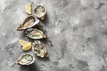Delicious fresh oysters with thyme and lemon on grey background © Pixel-Shot