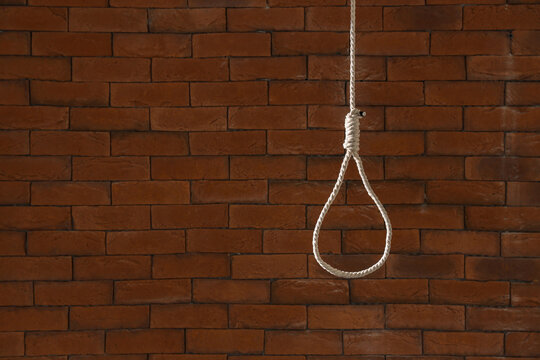 Hanging rope with loop on brick background. Suicide concept