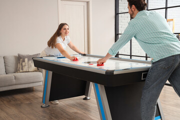Obraz premium Young woman with her husband playing air hockey at home
