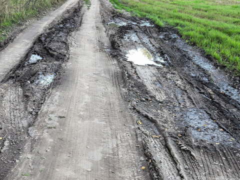 Deep tire ruts and muddy puddles on a rural dirt road