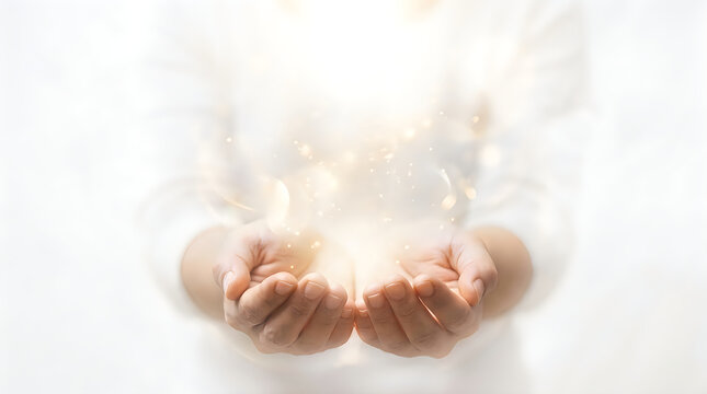 Closeup of cupped hands holding glowing golden light particles isolated on white background