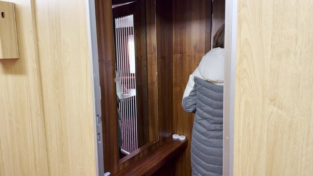 A woman opens a cabin door inside a cruise ship on the Neva River. She feels excited and eager to start her cozy vacation. The warm interior brings a joyful feeling.