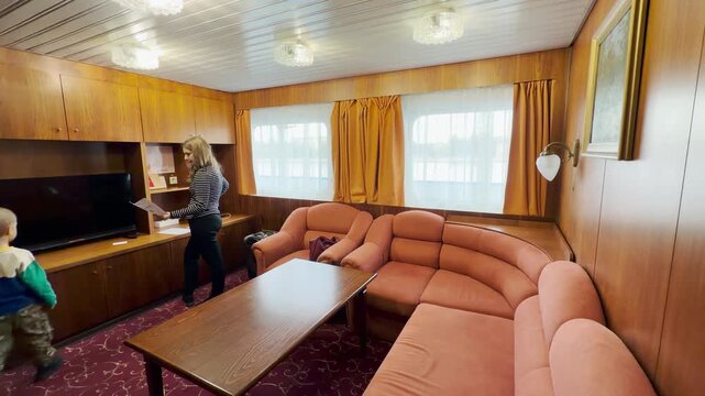 A woman and boy explore a spacious suite inside a Neva River cruise ship. They feel happy and excited in the cozy room. The warm atmosphere brings a joyful feeling.