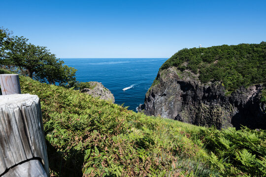 知床の断崖絶壁と青い海を進むボートの雄大な風景