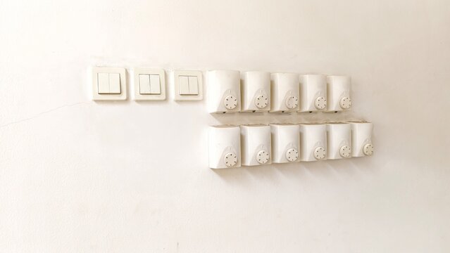 a collection of white electrical wall fixtures mounted in two rows on a plain, off-white wall