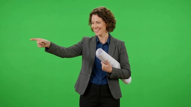 Smiling businesswoman in a gray blazer points aside while holding documents against a bright green background
