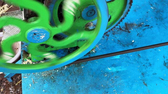 Rotating metal wheels of a traditional sugarcane juicer machine, showcasing the mechanical process used to extract fresh sugarcane juice