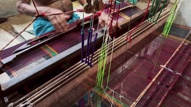 Close-up view of hands weaving fabric on a traditional handloom, showcasing skilled craftsmanship and India's rich textile heritage