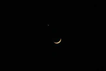 Elegant crescent phase, with one side illuminated by sunlight. The bright point near the upper left of the crescent is Venus. © Joshua Prasetyadi