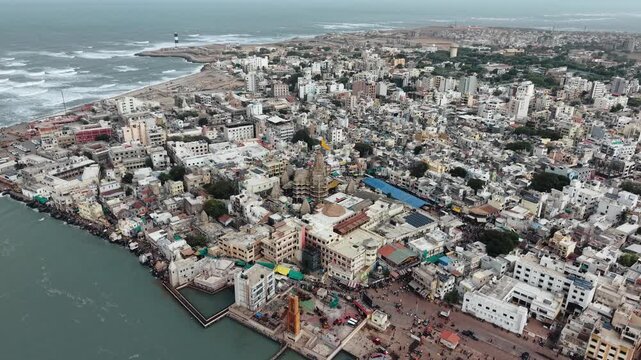A drone shot flying over the holy city of Dwarka, Gujarat, showing the iconic Dwarkadhish Temple (Jagat Mandir) situated near the coast and the Gomti River. The footage highlights the intricate temple