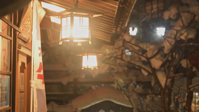 レトロな提灯の温かい明かりと雪を被った枝の渋温泉の夜景スローモーション