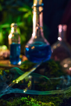 Ornate metal knife rests diagonally on old books with blue glass bottles softly blurred behind in a vertical fantasy photograph with moss and smoke for occult storytelling