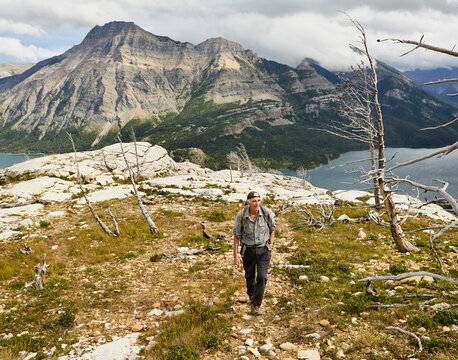 Senior man hiking among burnt trees in scenic Canadian Rockies, Waterton Lakes National Park, Canada