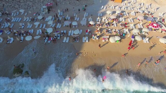 Aerial Kaputas Beach in Kas Antalya Turkey shows turquoise water, cliffs, umbrellas, and crowds.