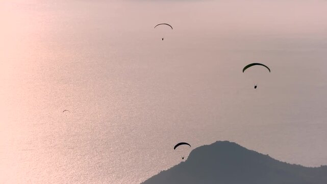 Paragliders cross a sunset sky above sea and islands near Fethiye, Turkey.