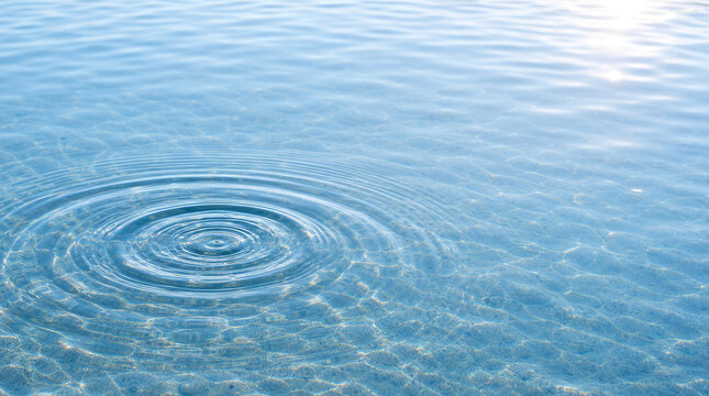 Circular ripple spreading across bright calm water surface