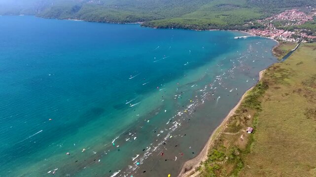 Aerial drone view of kiteboarders in Akyaka Gokova Bay Turkey with wind, waves, and beach.