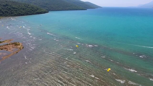 Windsurfing people glide across Gokova Bay Turkey sea waves during summer water sport.