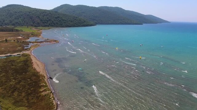 Aerial drone view of kiteboarders in Akyaka Gokova Bay Turkey with wind, waves, and beach.