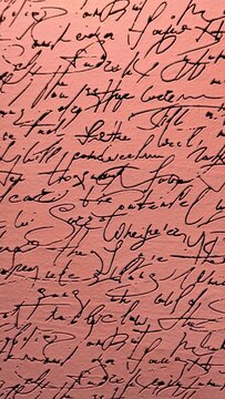 Abstract closeup of vintage cursive handwriting in black ink on a salmon pink textured background for creative design projects.