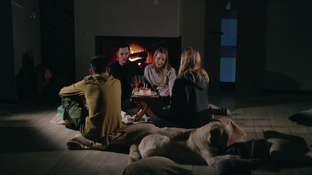 Friends Gather by Fireplace as Dog Rests on Pillows