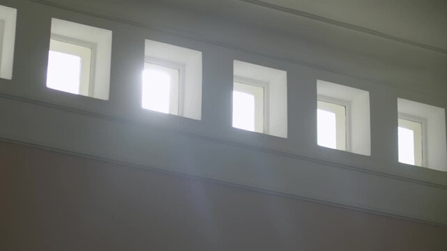 Minimal white interior wall with bright light pouring through five small square windows