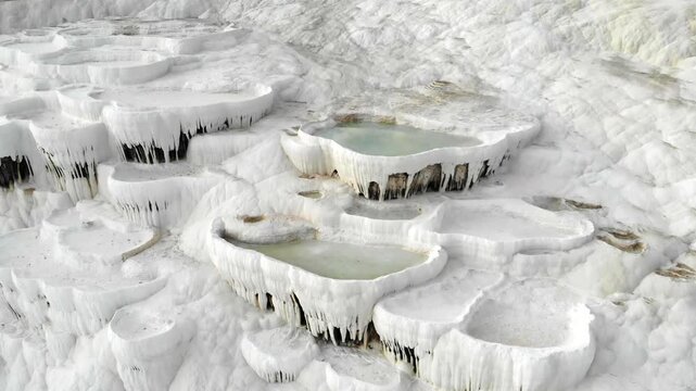 Aerial drone view of Pamukkale travertine pools in Denizli Turkey with white limestone bowls.