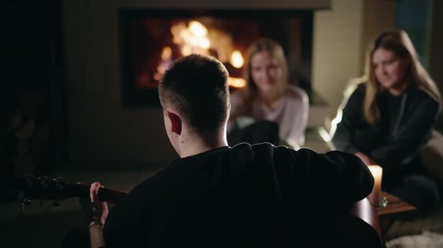Guitarist Playing for Two Women by a Glowing Fireplace