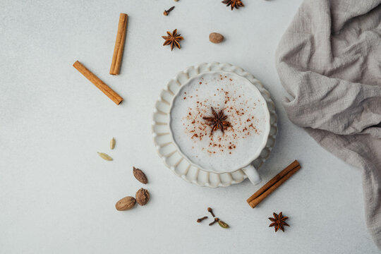 Chai latte with milk foam, cinnamon and star anise spices on a light background