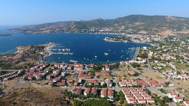 Aerial drone view of Foca harbor in Izmir Turkey with marina, boats, houses, and Aegean bay.