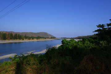 Obraz premium Natural Mountain View with Rocky Riverbank and Forested Hills