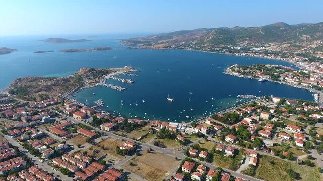 Aerial drone view of Foca harbor in Izmir Turkey with marina, boats, houses, and Aegean bay.
