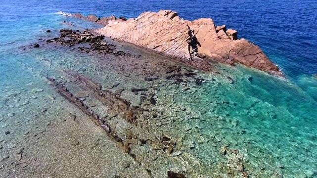 Aerial drone overhead of submerged rock and seamount in Chile with shallow turquoise water.
