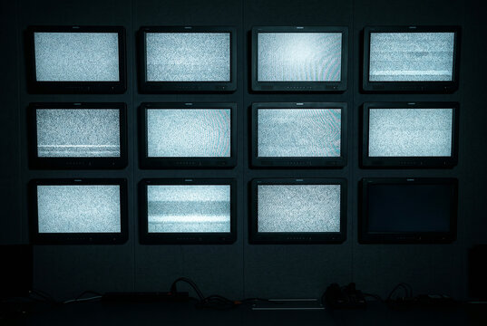 Wall of twelve vintage screens showing static noise, media noise concept