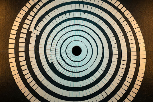 Spiral of pale blocks winding into a dark centre, endless cycle concept