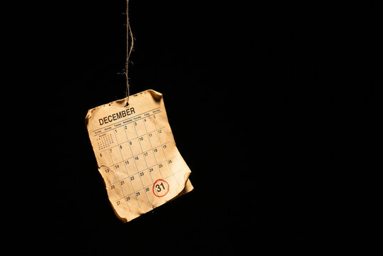Torn December calendar page hanging by a thread, year end concept