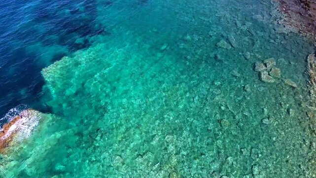Aerial drone overhead of submerged rock and seamount in Chile with shallow turquoise water.